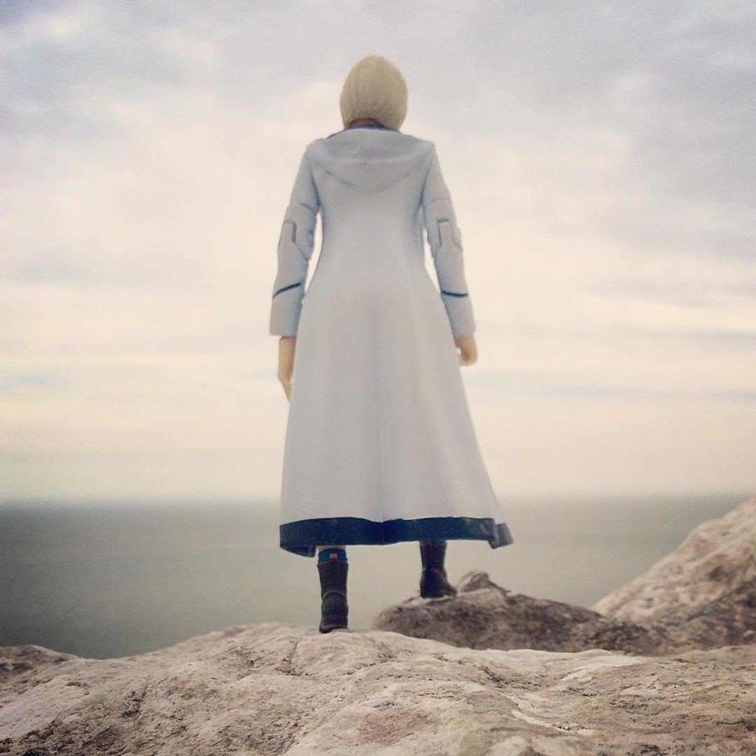 Image of a Thirteenth Doctor figurine on a rock looking out over a landscape